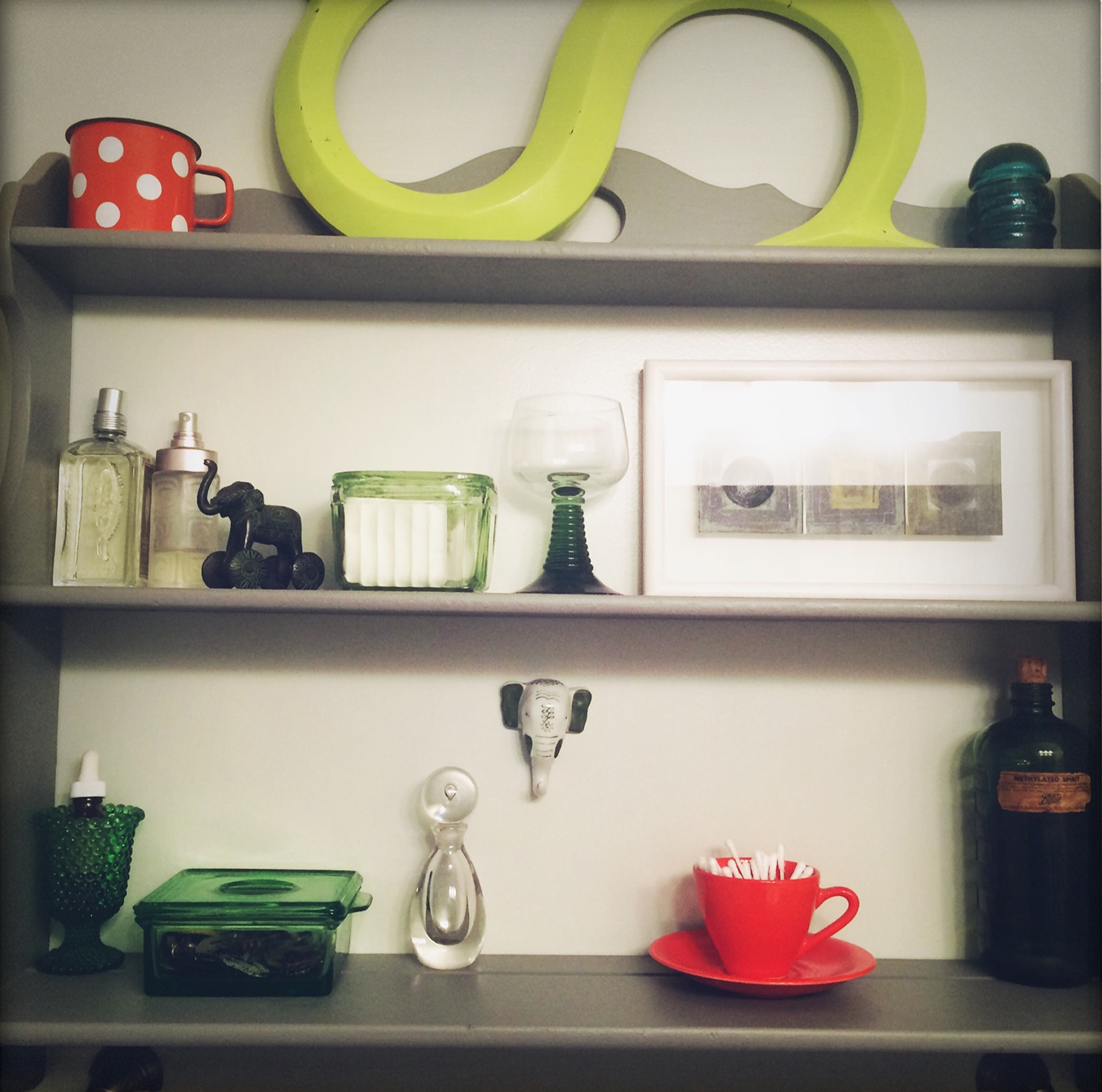 Here’s a peek at my bathroom shelves (I know! Seems strange but my bathroom is one of my favourite rooms in my apartment. Really!) as they are an indicator of my eclectic taste. I love objects and I collect a variety of things, each with their own significance. I could spend hours happily rearranging all of these items and then adding and subtracting more and less. I adore composition and it doesn’t always have to be letterforms. The sentiments are often emotional, such as the polka-dotted tin cup that I loved from my childhood, the porcelain elephant head from India, the electrical insulator and the german wine glass from my great grandmother’s house, or the painting from Martin Andrews, a Typography Professor from the University of Reading. Other objects are admired for their color, the orange cup and saucer from a thrift store; their form, my grandmother’s perfume bottle; or their history, the vintage medicine bottle from a boot sale in Reading.