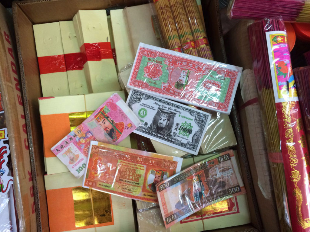 Different designs of paper money at the small Sheung Wan store. Below the banknotes are bundles of blank paper money.