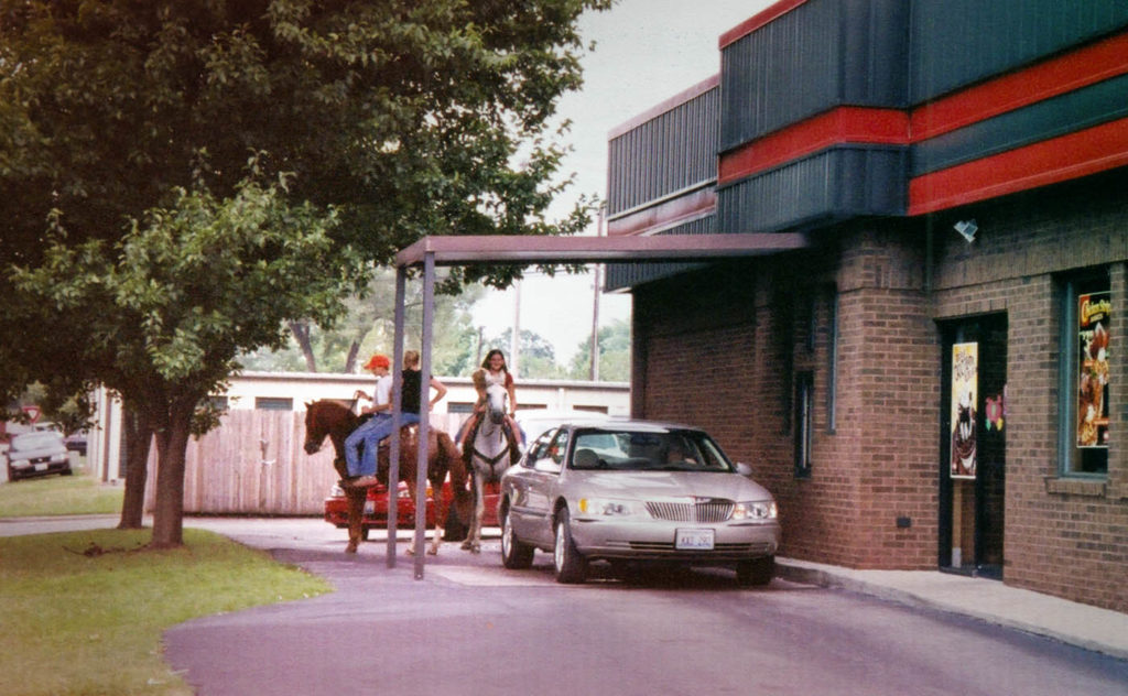 3 horseback riders waiting in a Dairy Queen drive thru line
