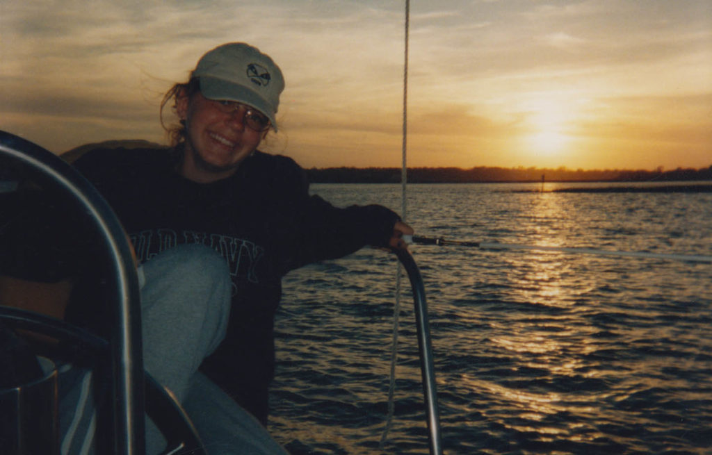 Young woman relaxing on a sailboat at sunset