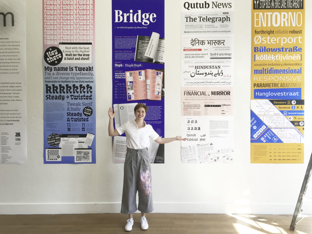 2,60 meter long Bridge poster at the TypeMedia exhibition 2018 surrounded by classmates posters. Mona Franz is standing in front of her poster. 3D elements were made by Studio Meeer.