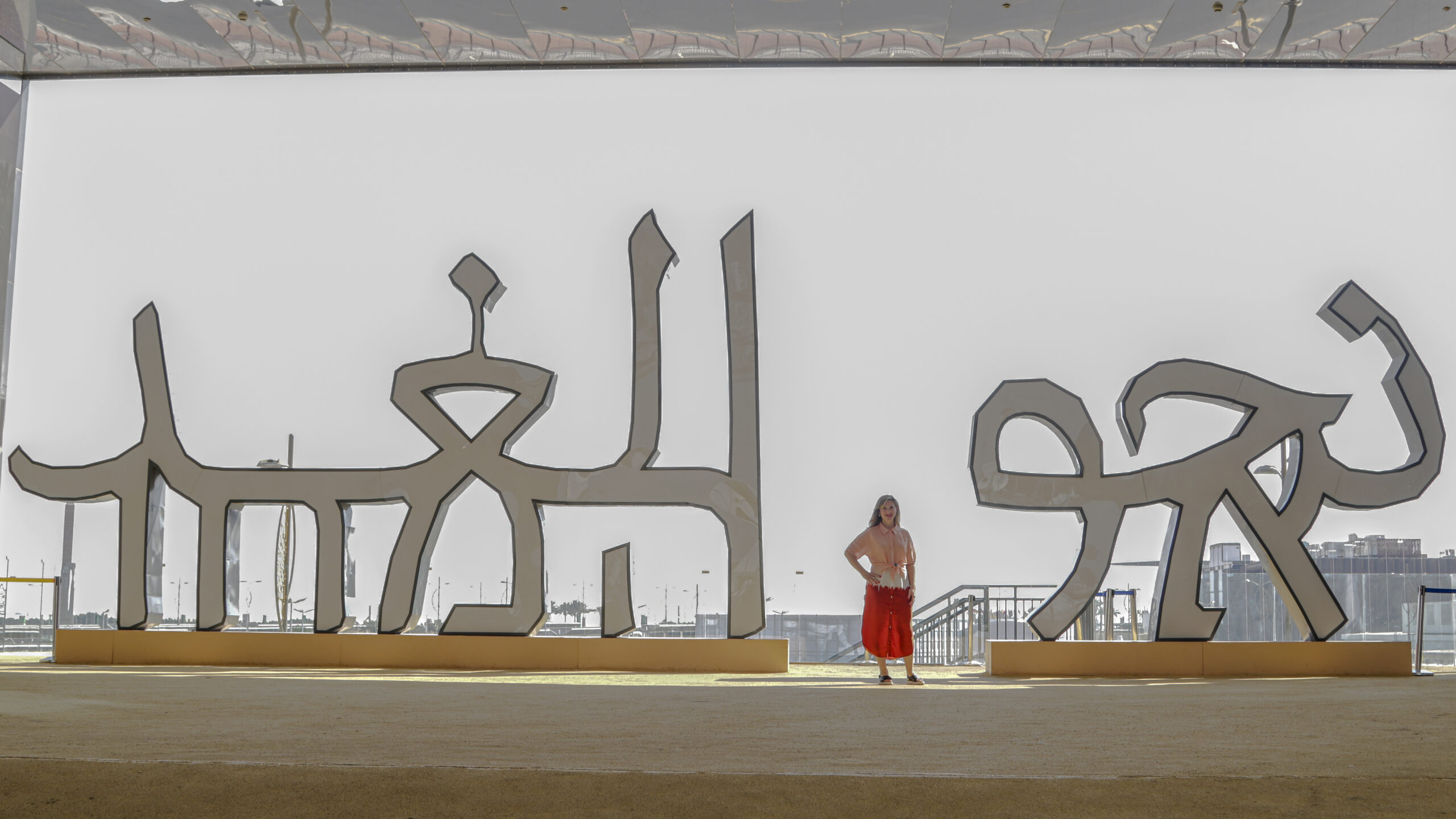 woman standing next to large sculpture of letterforms