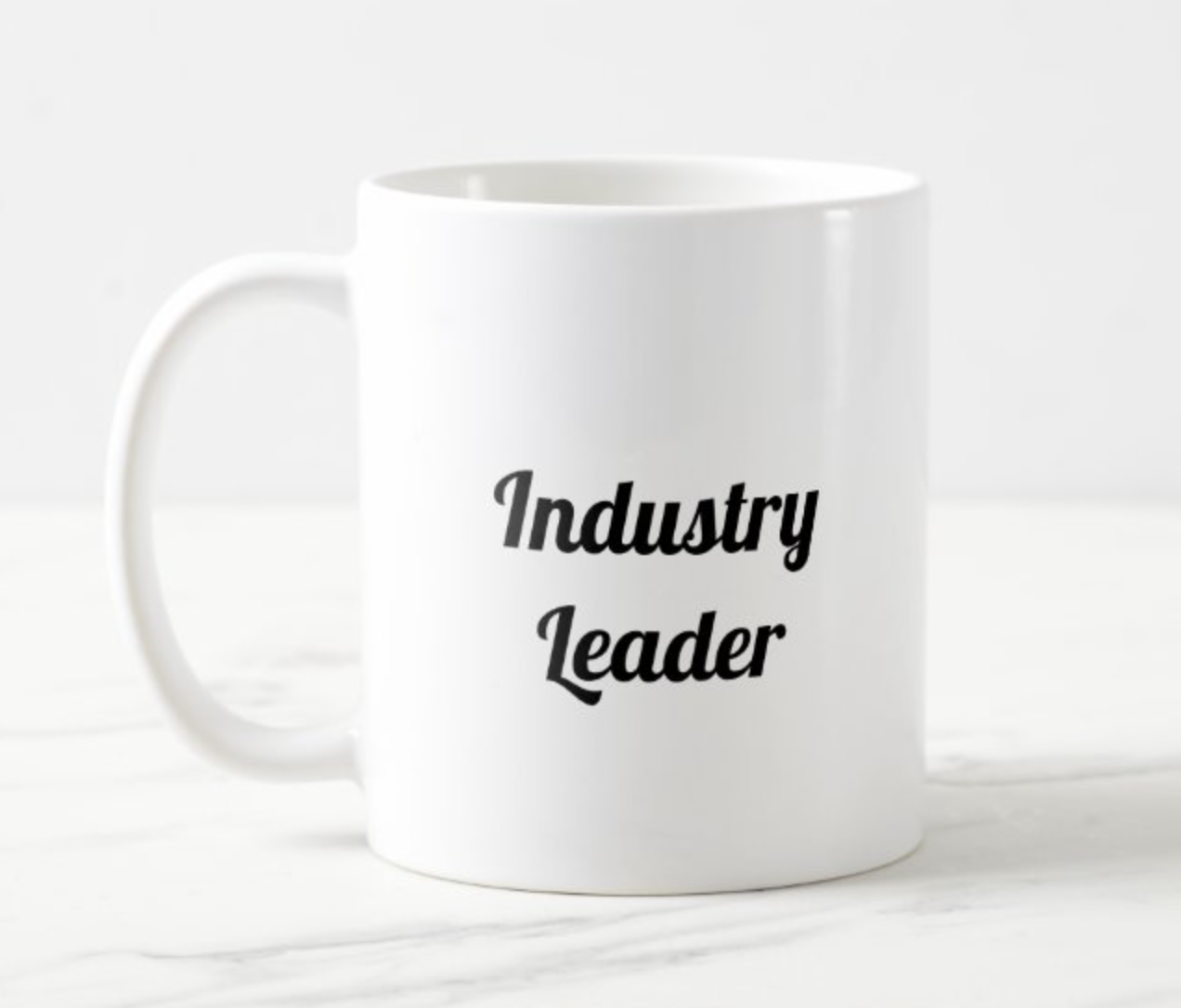 a white coffee mug with the text, Industry Leader, set on it in the font Lobster