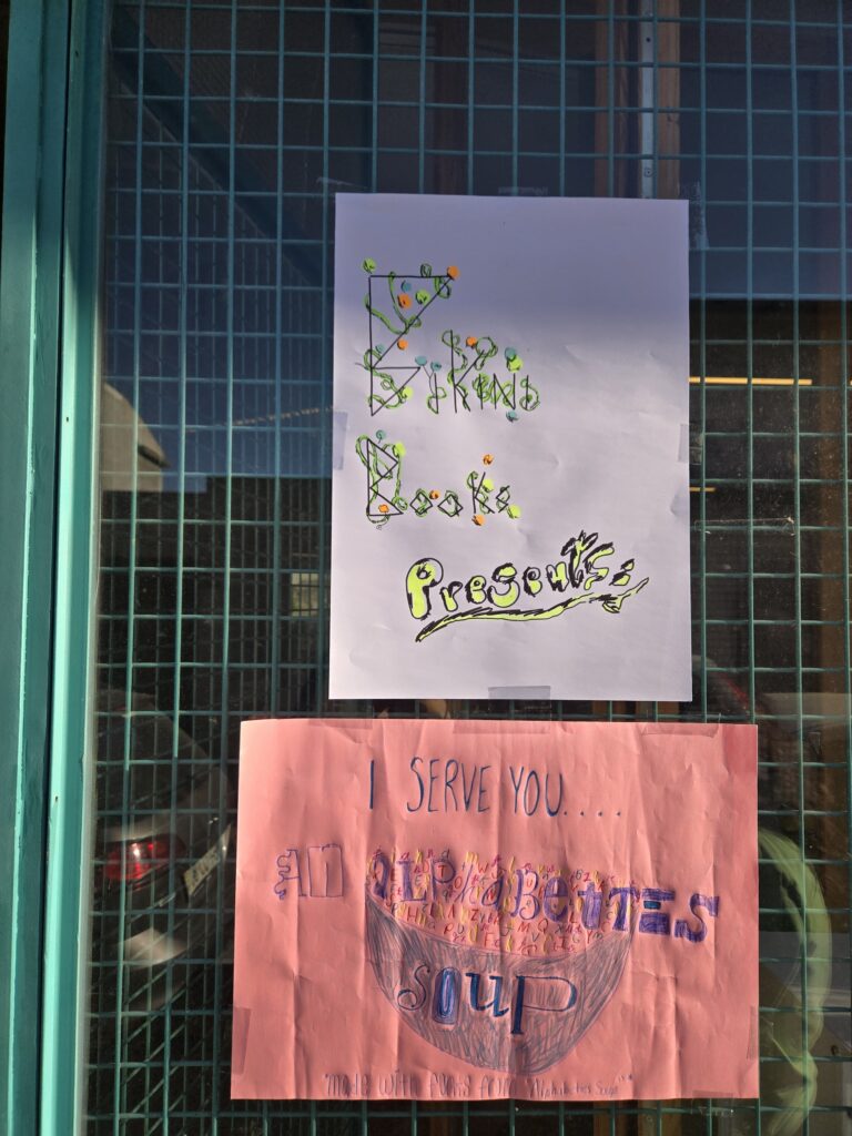 hand drawn signs made by children that say Bikini Books Presents and I Serve you Alphabettes Soup with a drawing of a soup bowl on pink paper